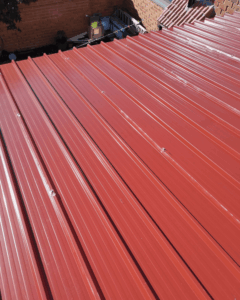 Cubierta de panel sándwich 5 grecas color rojo teja para porche de vivienda en Tarragona