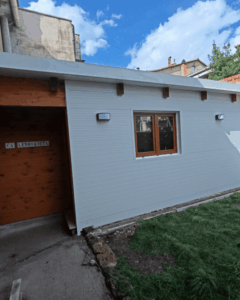 Fachada de panel sándwich de tornillería oculta blanca en vivienda auxiliar