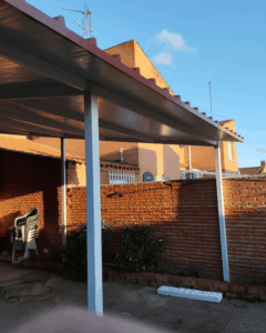 Porche residencial de gran formato terminado con panel sándwich de cubierta 5 grecas rojo teja en Tarragona
